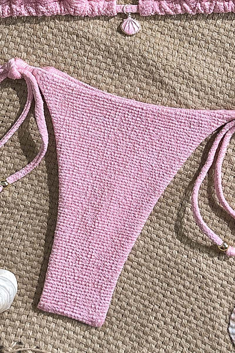 Pink textured string thong bikini bottom on a woven surface