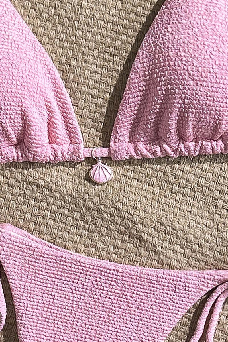 Close-up of a pink textured micro bikini set on a textured surface.