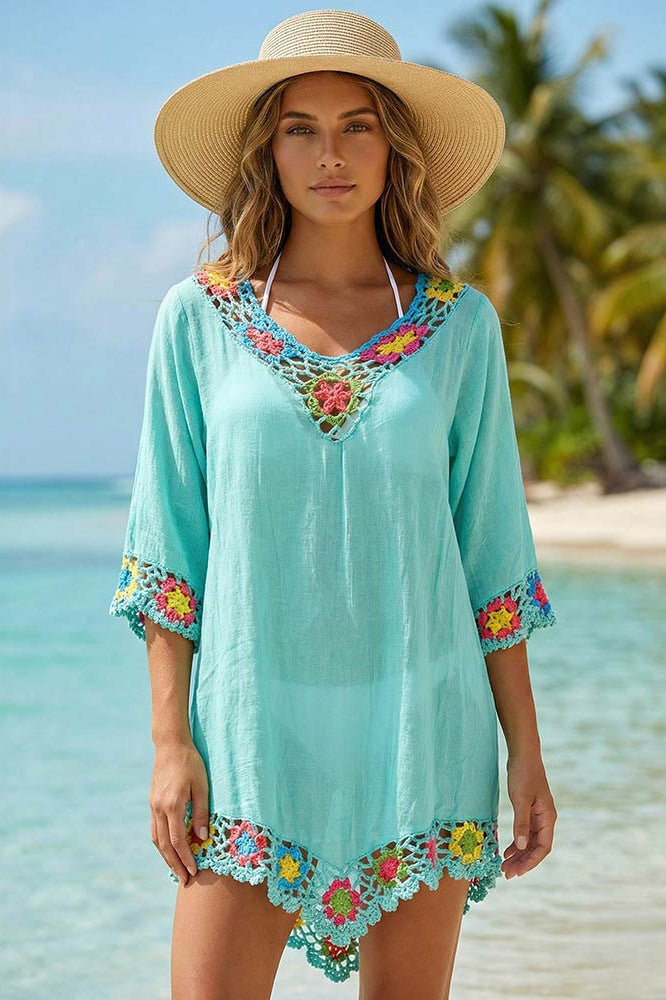 Sierra Shine CEO of Berrydog Bikinis wearing a turquoise cover-up with floral lace details and micro thong bikini underneath it on a beach.