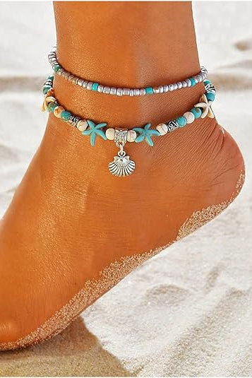 Anchored foot with beaded anklets on a sandy background