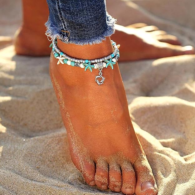 Anchored foot with starfish anklets on a sandy background